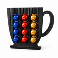 Black cup-shaped coffee capsule holder displaying blue, red and gold capsules on a white background