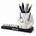 Personalised doctor pen holder with white coat, decorative stethoscope and name on a black base, shown on a white background.