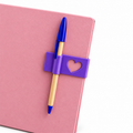 Heart-detail bookmark and pen holder displayed on a pink notebook